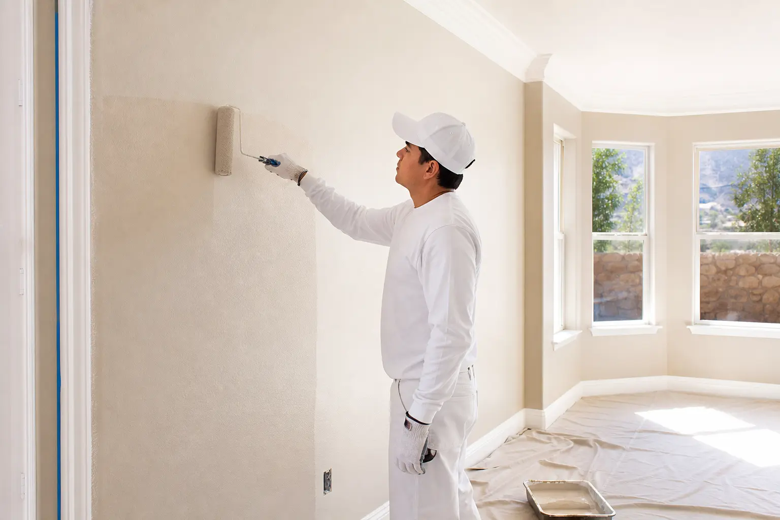Professional house painter rolling fresh paint onto a smooth interior wall in El Paso
